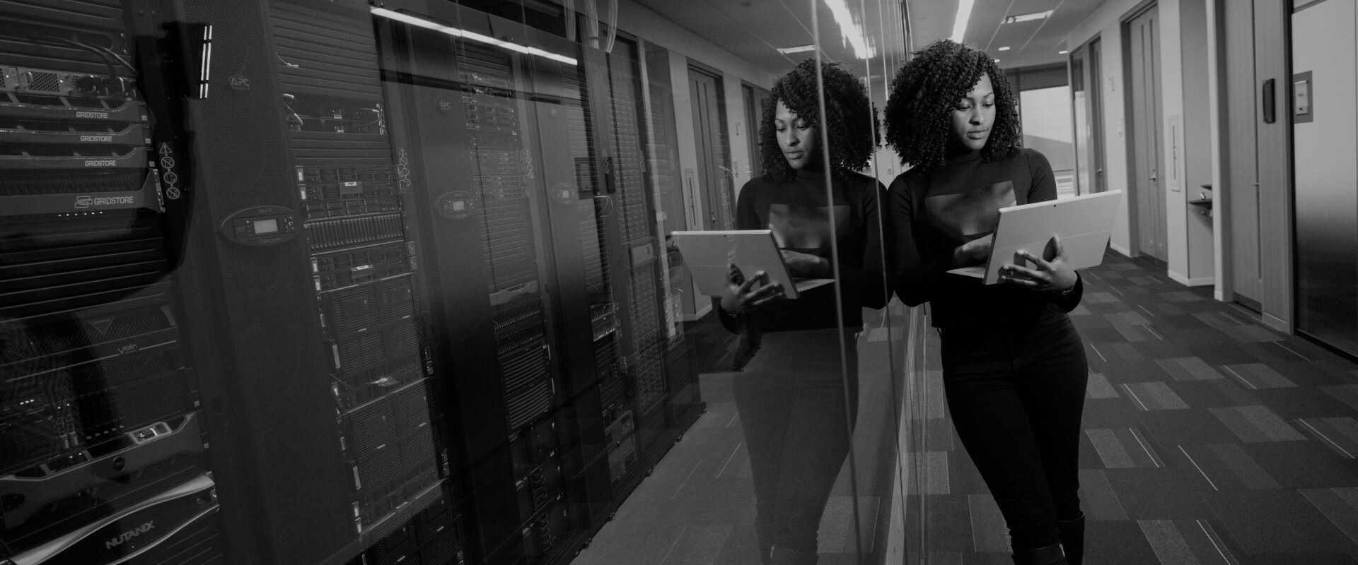 Woman leaning against glass wall using laptop